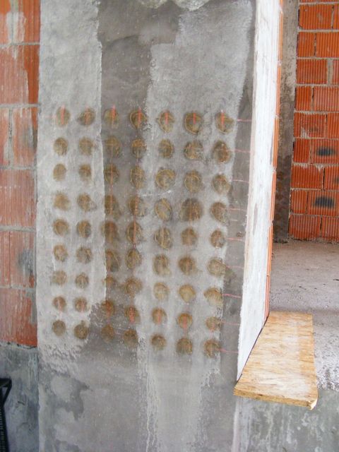 Stâlp de beton cu o grilă de puncte marcate pentru încercarea cu sclerometrul, lângă zidărie de cărămidă.
